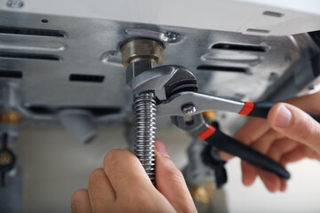 Man repairing gas boiler with waterpump plier, closeup