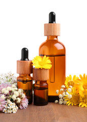 Bottles of essential oils and different wildflowers on wooden table against white background