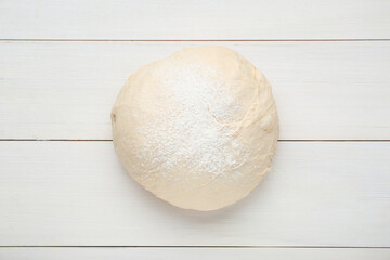 Fresh yeast dough with flour on white wooden table, top view