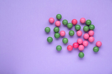 Many bright chewy gumballs on lilac background, flat lay. Space for text