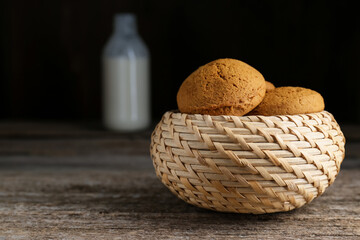 Wicker basket with delicious oatmeal cookies on wooden table. Space for text