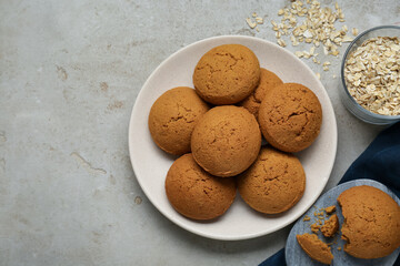 Delicious oatmeal cookies and flakes on light grey table, flat lay. Space for text