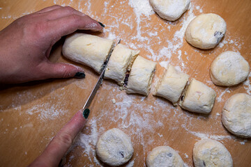 Female hands cut with knife raw sweet dough, the process of making cheesecakes
