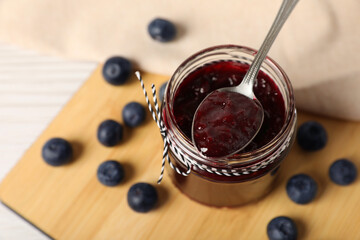 Spoon with delicious blueberry jam and fresh berries on wooden table, above view. Space for text