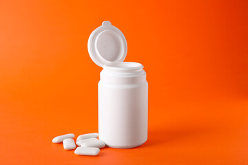 Jar with chewing gums on orange background