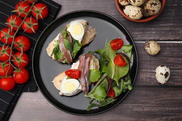 Delicious bruschettas with anchovies, cream cheese, eggs and tomatoes on wooden table, flat lay