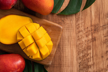Fresh mango fruit with leaves over dark wooden table background.