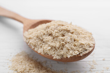 Beer yeast flakes and spoon on white wooden table, closeup