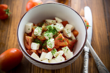 salad of fresh ripe tomatoes with mozzarella and spices in a bowl