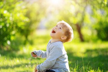 Cute laughing child sitting on the green spring meadow.