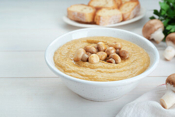 Delicious mushroom cream soup on white wooden table
