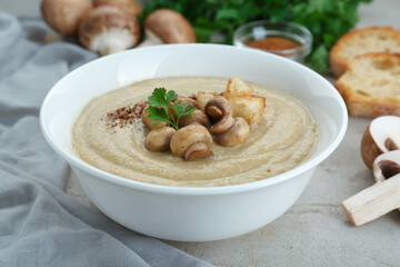 Delicious cream soup with mushrooms and croutons on beige textured table, closeup