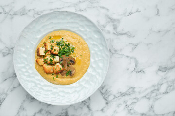Delicious cream soup with mushrooms and croutons on white marble table, top view. Space for text