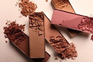 Different crushed eye shadows on beige background, flat lay