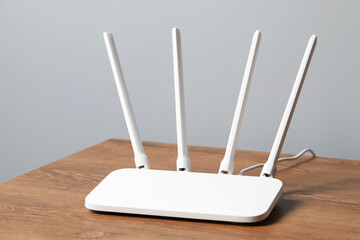 New white Wi-Fi router on wooden table indoors