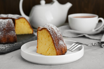 Piece of homemade yogurt cake with powdered sugar on light grey table