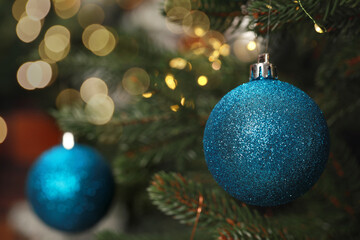 Fototapeta na wymiar Blue Christmas ball hanging on fir tree branch, closeup. Space for text