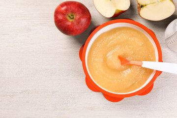 Healthy baby food. Bowl with delicious apple puree and fresh fruits on white wooden table, flat lay. Space for text