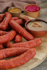 Delicious sausages, ketchup, mustard and horseradish on wooden table, closeup