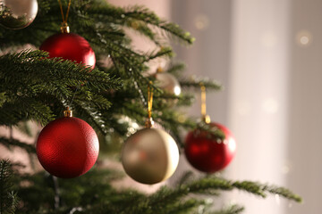 Christmas tree with beautiful baubles on blurred background, closeup. Space for text