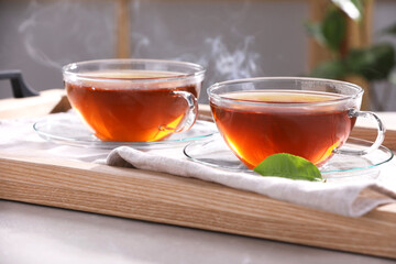 Aromatic hot tea in glass cups on light grey table indoors, closeup