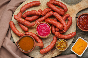 Delicious sausages, ketchup, mustard and horseradish on wooden table, flat lay