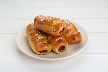 Delicious sausage rolls on white wooden table