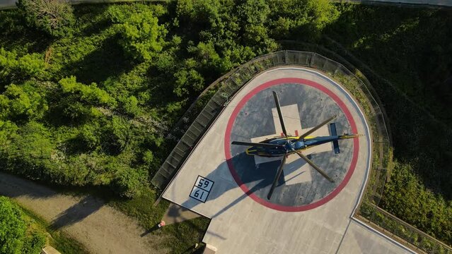 Helicopter landed on pad near hospital building, aerial top down ascend view