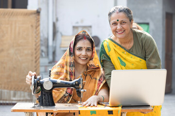 Female inspector guiding textile worker by using laptop.