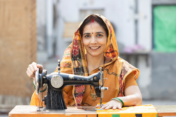 Indian rural woman using sewing machine at home