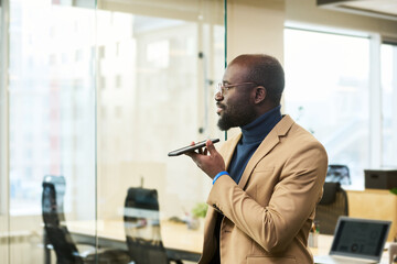 Young elegant African American chief executive officer or manager holding mobile phone below his...