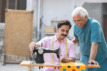 Senior teacher helping a man learning to use the sewing machine.