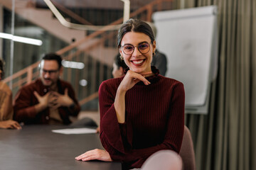 Fototapeta premium Portrait of a cheerful businesswoman, sitting with colleagues in the meeting room.