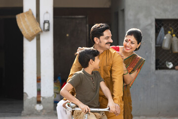 Portrait of happy Indian parents with son riding on bicycle