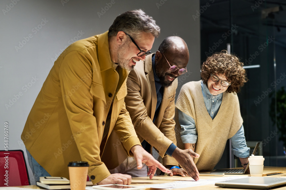 Aufkleber Group of three intercultural brokers in smart casualwear discussing document with financial data while bending over workplace