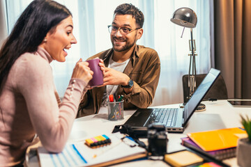 Young couple of photographers working with laptop at the working place with computers in the studio