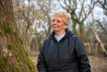 Beautiful mature woman outdoors walking in a woodland in winter 