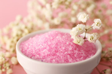 Aromatic sea salt and beautiful flowers on pink background, closeup