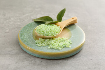 Aromatic sea salt and green leaves on grey textured table