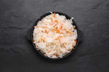 Bowl of tasty sauerkraut on black table, top view