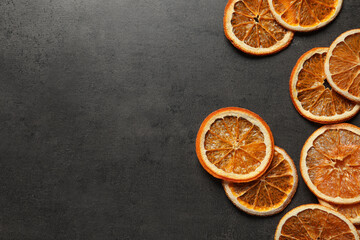 Dry orange slices on black table, flat lay. Space for text