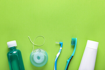 Flat lay composition with dental floss and different teeth care products on green background, space...