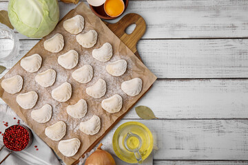 Raw dumplings (varenyky) with tasty filling and ingredients on white wooden table, flat lay. Space for text
