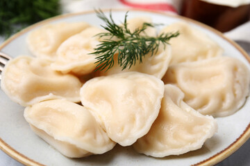 Fototapeta na wymiar Cooked dumplings (varenyky) with tasty filling and dill on plate, closeup
