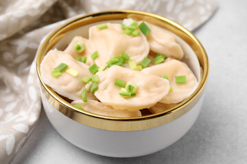 Cooked dumplings (varenyky) with tasty filling and green onion on light table, closeup