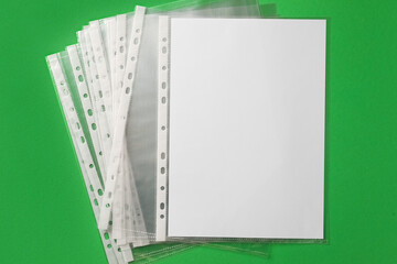 Punched pockets with paper sheet on green background, flat lay