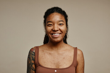 Young black woman smiling at camera standing on neutral beige background