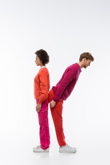 side view of interracial couple in magenta color clothes showing k letter on white background.