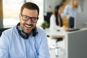 Portrait of smiling operator agent with headset around his neck at office