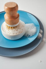 dishwashing brushes, towel and detergent on table with white walls. Home comfort. Household equipment.